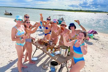 group of ladies enjoying a low country boil dinner on the beach